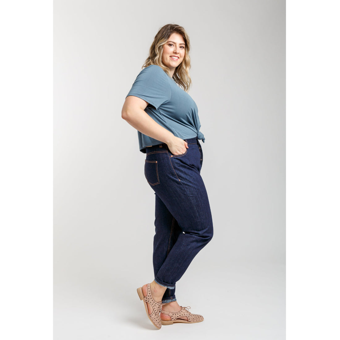 Woman wearing a blue top and dark jeans on a white background