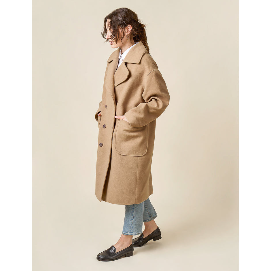 Woman wearing a beige coat on a plain background