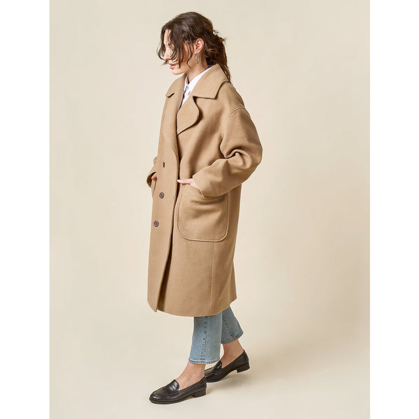 Woman wearing a beige coat on a plain background
