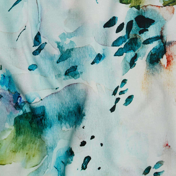 Close-up of fabric with watercolor floral pattern in blue, green, and black on a white background.