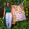 Woman holding a colorful quilt in a garden setting