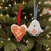 Decorative heart and penguin-shaped ornaments with floral patterns hanging in a Christmas tree.