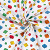 Roll of fabric with colorful Lego block pattern on a white background