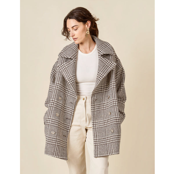 Woman wearing a checkered coat on a beige background