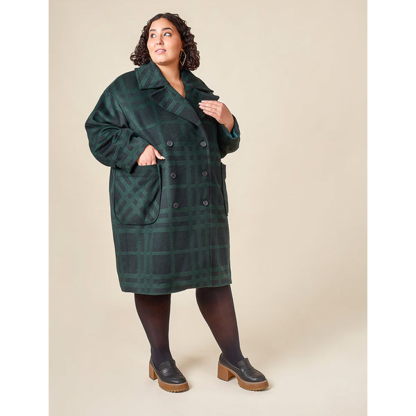 Woman wearing a green plaid coat against a beige background