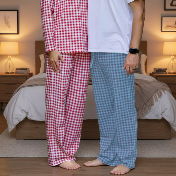 Two people wearing red and blue checkered pajama pants standing in a bedroom.