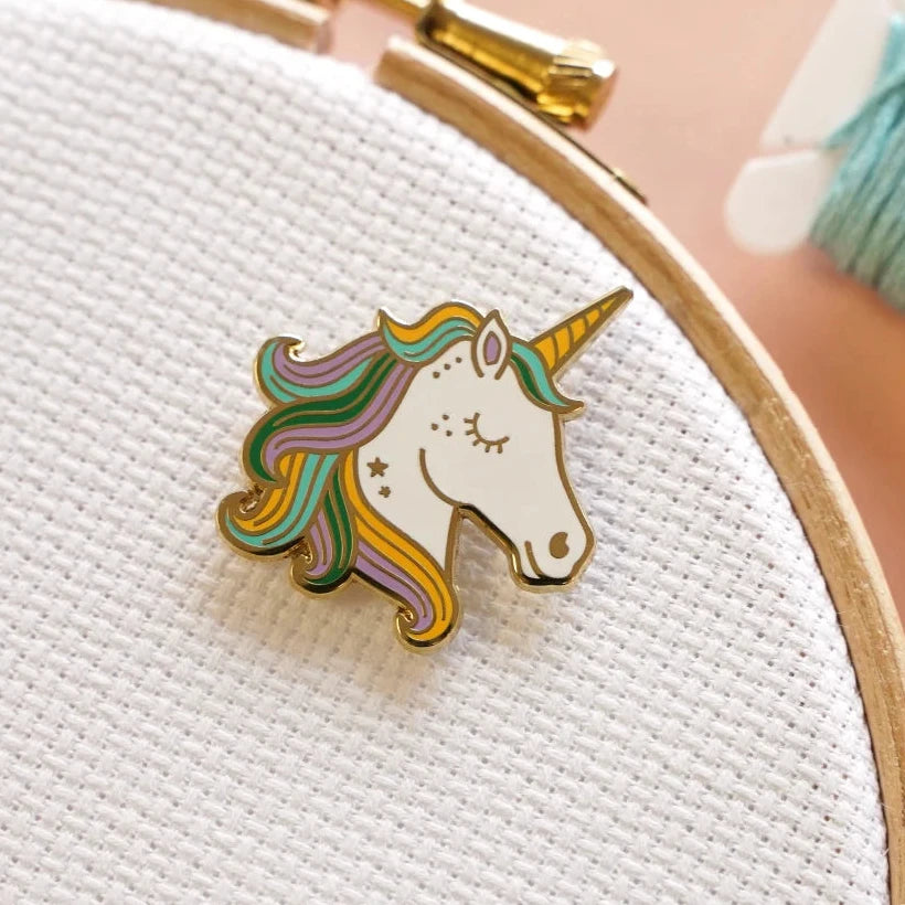 Colorful unicorn pin on a white fabric background