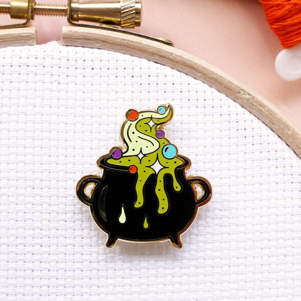Colorful cauldron pin on a white fabric background