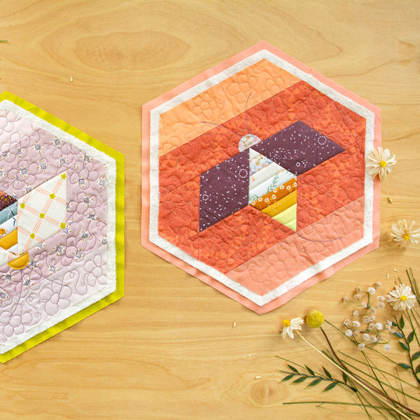 Two hexagonal coasters on a wooden surface with floral decorations.